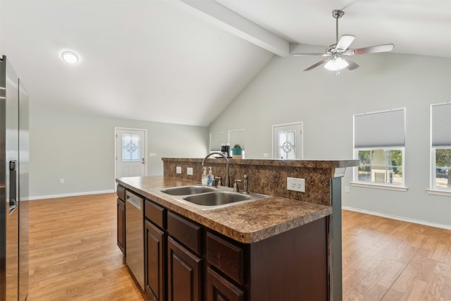 kitchen featuring beam ceiling, sink, stainless steel appliances, an island with sink, and light hardwood / wood-style floors