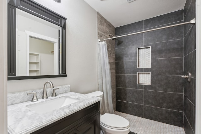 bathroom featuring a textured ceiling, vanity, toilet, and curtained shower