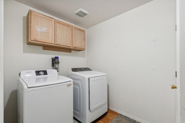 clothes washing area with dark wood-type flooring, cabinets, and independent washer and dryer