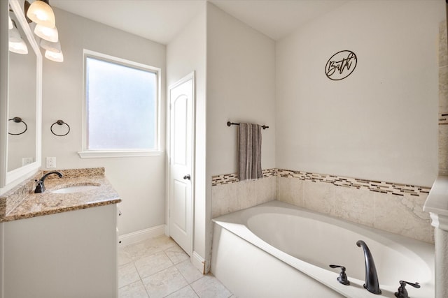 bathroom featuring baseboards, vanity, and a garden tub