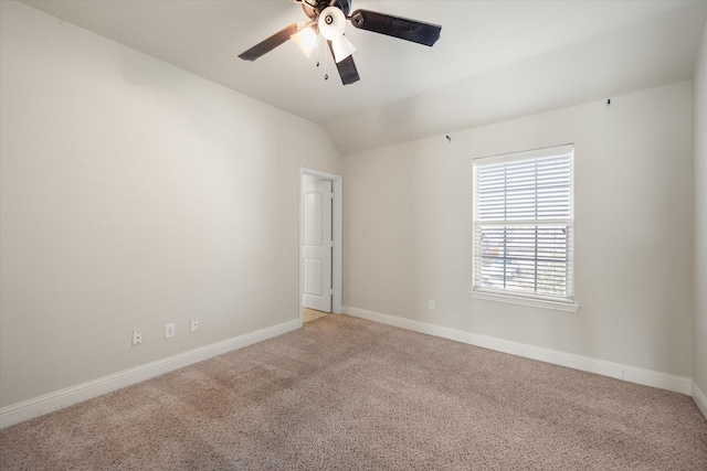 empty room with baseboards, lofted ceiling, a ceiling fan, and light colored carpet