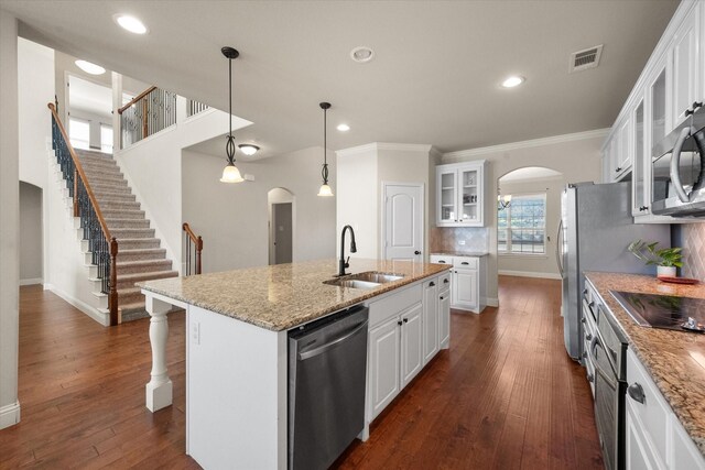 kitchen featuring stainless steel appliances, decorative backsplash, a sink, arched walkways, and visible vents