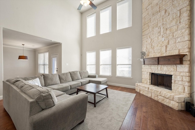 living area with crown molding, baseboards, dark wood-style floors, ceiling fan, and a fireplace