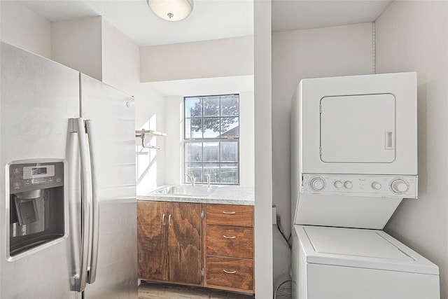 clothes washing area with sink and stacked washer and clothes dryer