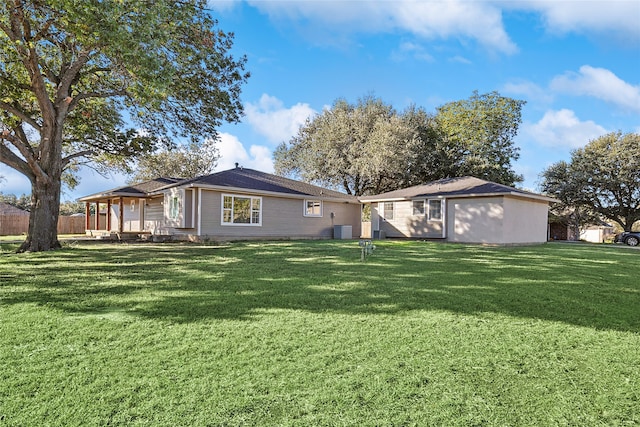 rear view of property featuring a lawn and central AC unit