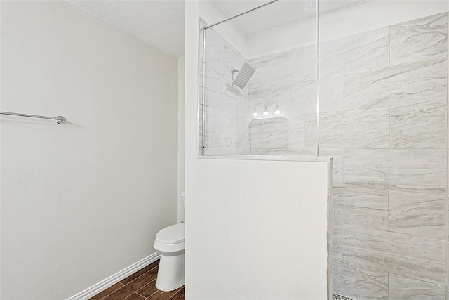 bathroom with toilet, wood-type flooring, and a tile shower