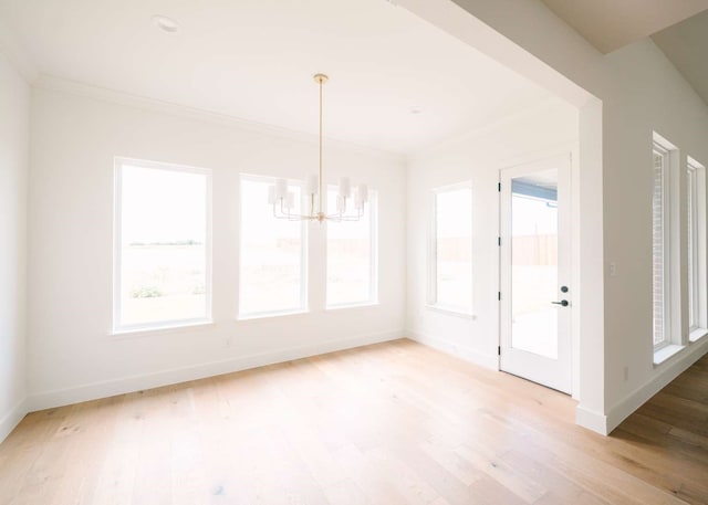 unfurnished dining area with light wood-type flooring, crown molding, and an inviting chandelier