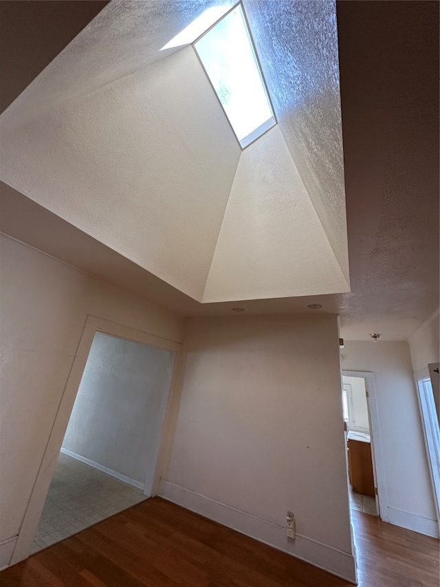 additional living space featuring a textured ceiling and light wood-type flooring