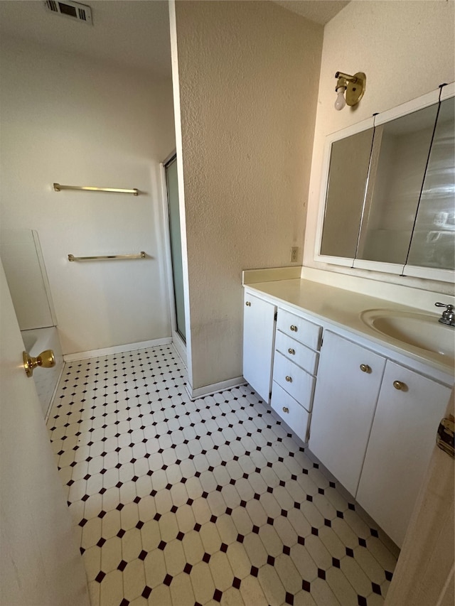 bathroom featuring vanity and a shower with door