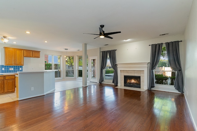 unfurnished living room with ceiling fan, light hardwood / wood-style flooring, plenty of natural light, and a tiled fireplace