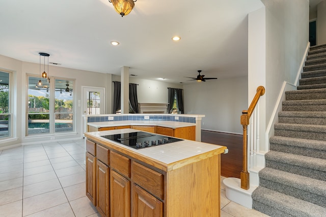 kitchen featuring light tile patterned floors, black electric cooktop, a kitchen island, and hanging light fixtures