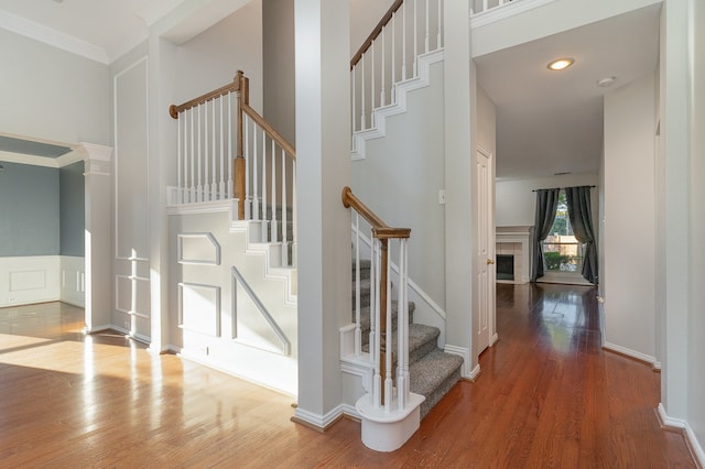 stairway featuring a tiled fireplace, ornamental molding, and hardwood / wood-style flooring