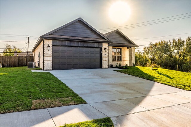 view of front of home featuring cooling unit, a garage, and a front lawn