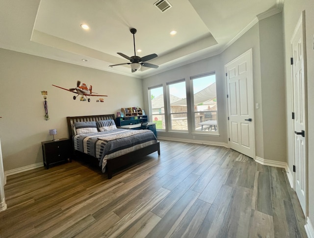 bedroom with a tray ceiling, crown molding, ceiling fan, and wood-type flooring