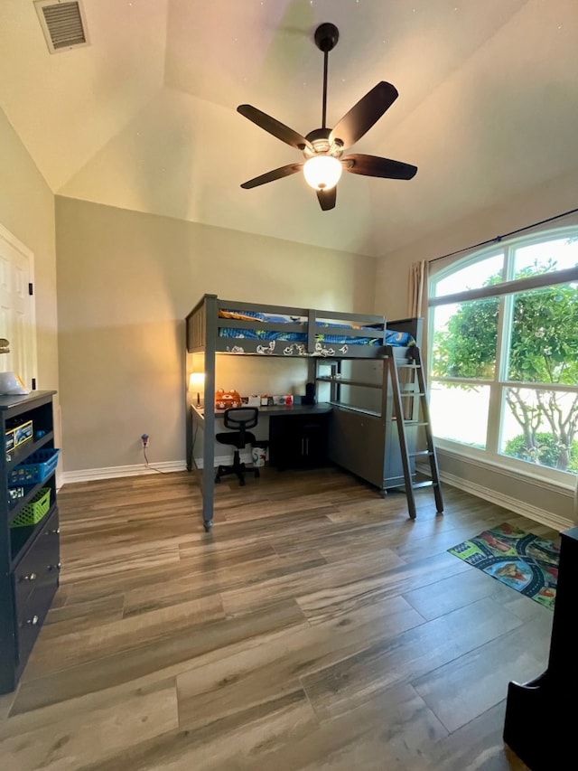 bedroom with built in desk, hardwood / wood-style flooring, vaulted ceiling, and ceiling fan