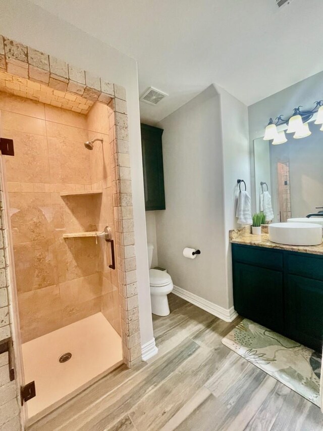 bathroom featuring hardwood / wood-style flooring, vanity, toilet, and a shower with door