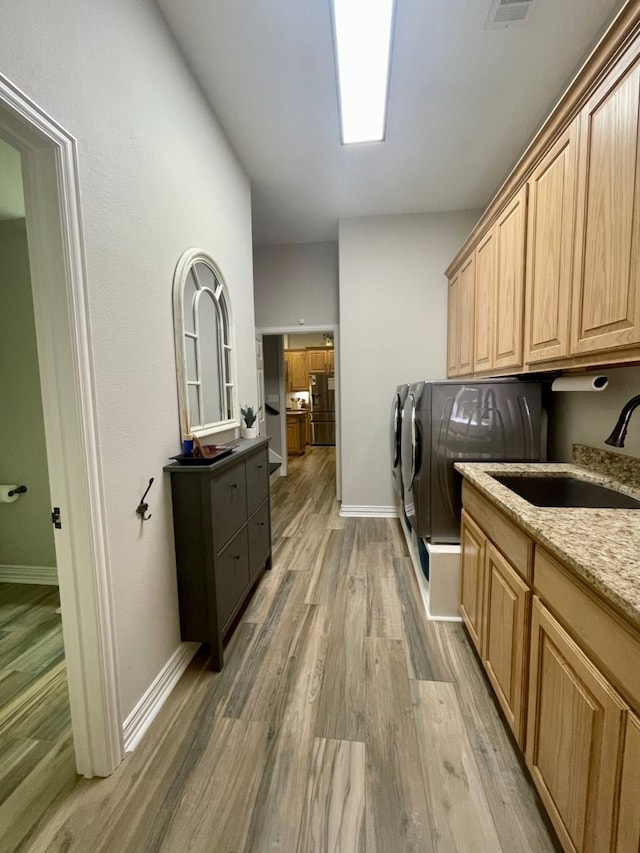 laundry room featuring cabinets, wood-type flooring, separate washer and dryer, and sink