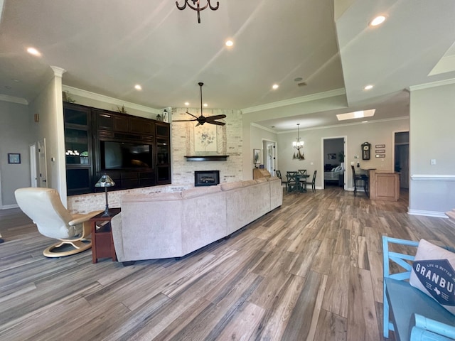 living room featuring hardwood / wood-style floors, ceiling fan with notable chandelier, and ornamental molding