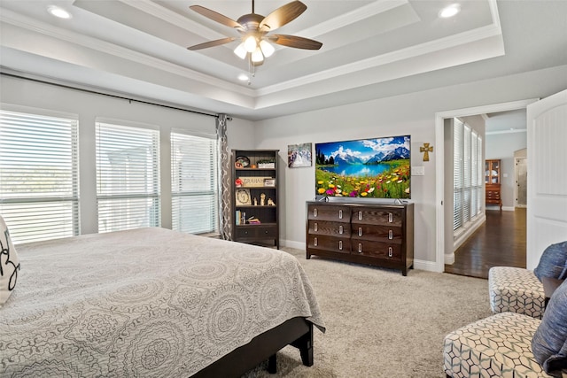 carpeted bedroom with ceiling fan, ornamental molding, and a tray ceiling