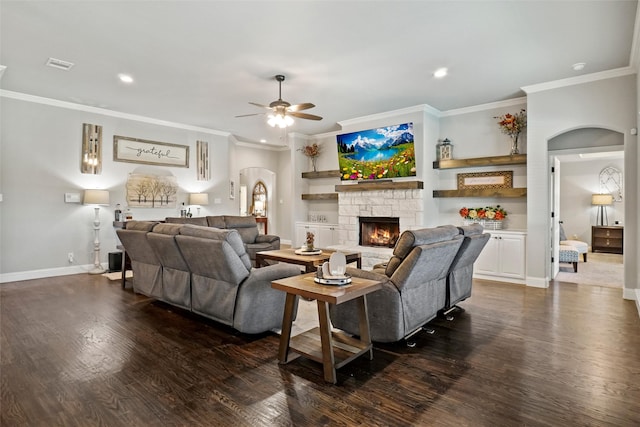 living room with a fireplace, crown molding, ceiling fan, and dark wood-type flooring