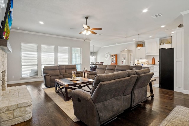 living room featuring ceiling fan, a fireplace, ornamental molding, and dark wood-type flooring