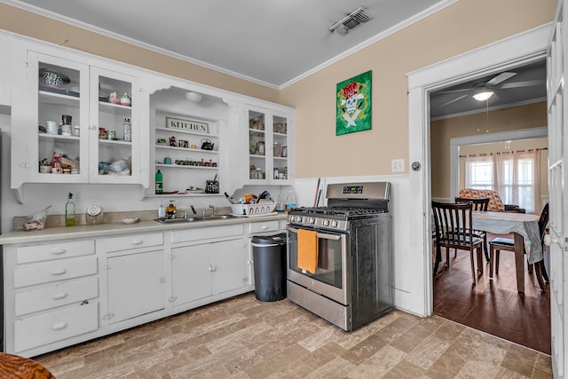 kitchen with crown molding, sink, ceiling fan, gas stove, and white cabinetry