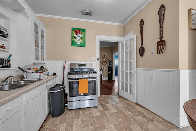 kitchen featuring white cabinets, light hardwood / wood-style floors, crown molding, and gas range