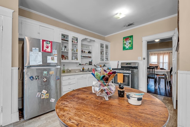 kitchen featuring stainless steel appliances, white cabinetry, and ornamental molding