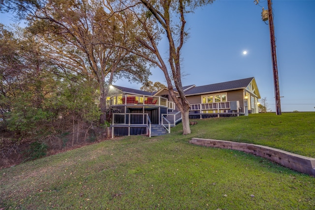 rear view of house featuring a wooden deck and a yard