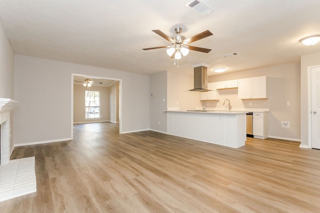 unfurnished living room featuring a fireplace, light hardwood / wood-style floors, ceiling fan, and sink