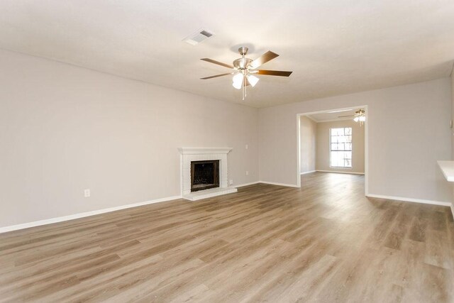 unfurnished living room featuring a fireplace, ceiling fan, and light hardwood / wood-style flooring