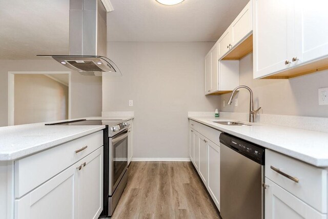 kitchen with sink, stainless steel appliances, kitchen peninsula, island exhaust hood, and light wood-type flooring