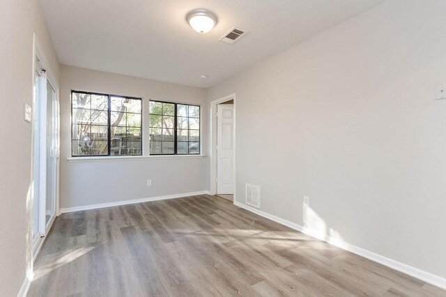 empty room featuring baseboards, visible vents, and wood finished floors