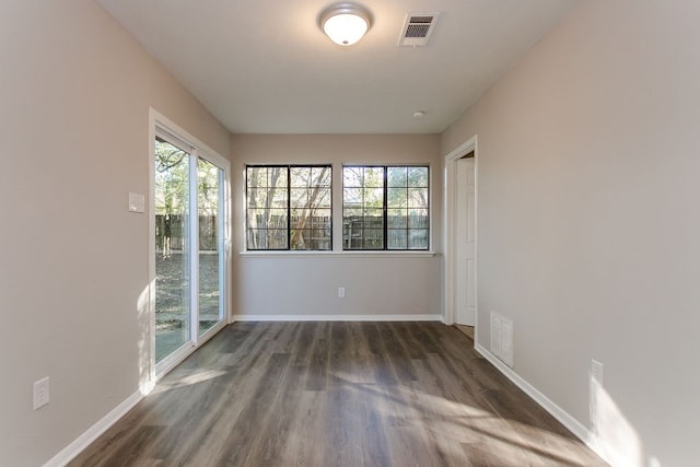 unfurnished room featuring baseboards, visible vents, and wood finished floors