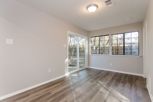 empty room featuring baseboards, visible vents, and wood finished floors