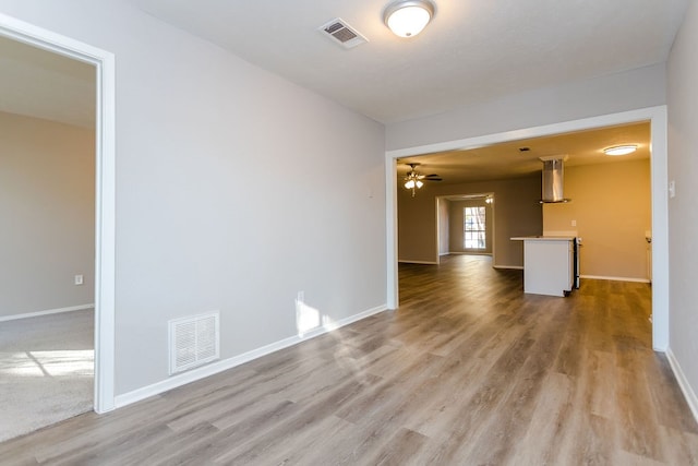 empty room featuring baseboards, visible vents, and light wood finished floors