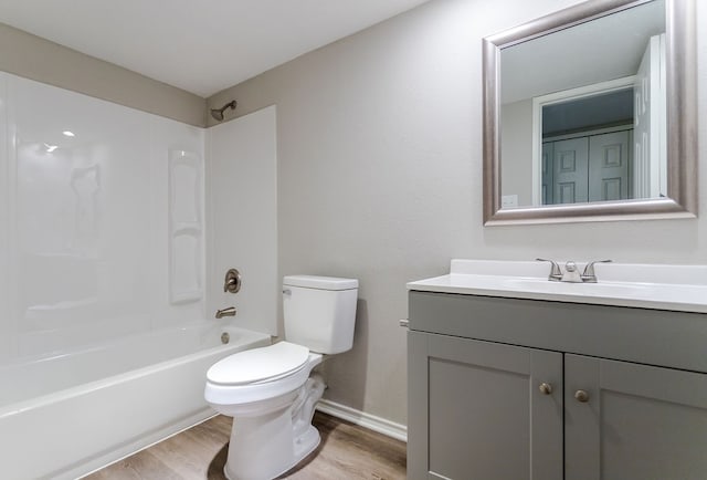 full bath featuring toilet, wood finished floors, vanity, baseboards, and  shower combination