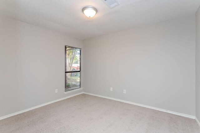 empty room featuring light carpet, visible vents, and baseboards