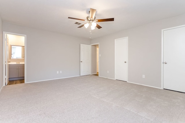 unfurnished bedroom featuring multiple closets, light colored carpet, visible vents, and baseboards