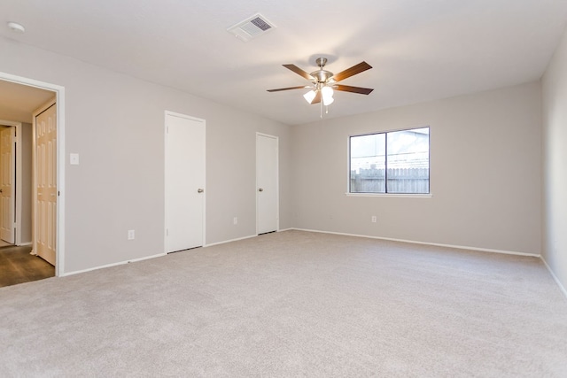 carpeted spare room with ceiling fan, visible vents, and baseboards