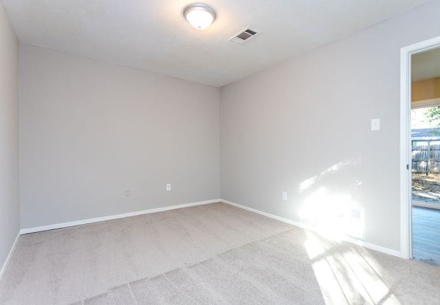 carpeted spare room featuring visible vents and baseboards