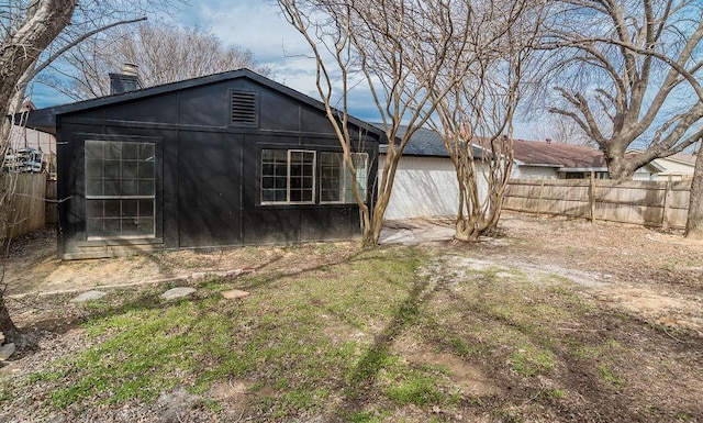 back of house with a chimney and fence