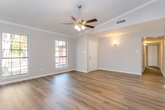 empty room featuring baseboards, visible vents, ornamental molding, wood finished floors, and vaulted ceiling