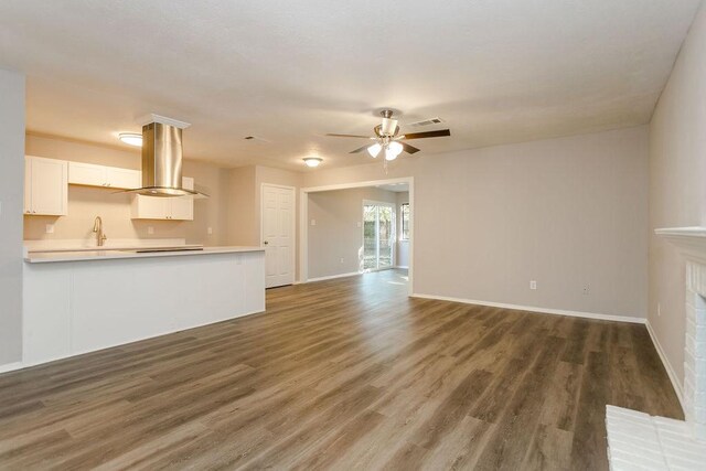 unfurnished living room featuring dark hardwood / wood-style floors, a fireplace, sink, and ceiling fan