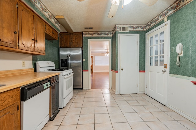 kitchen with a textured ceiling, white appliances, light tile patterned floors, and ceiling fan