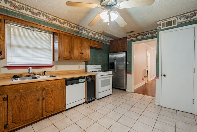 kitchen featuring a textured ceiling, ceiling fan, white appliances, and sink