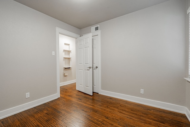 unfurnished room with dark wood-type flooring