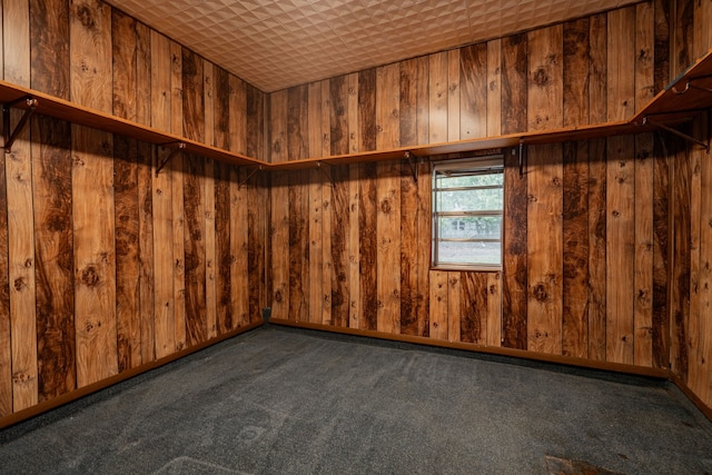 unfurnished room with dark colored carpet and wood walls