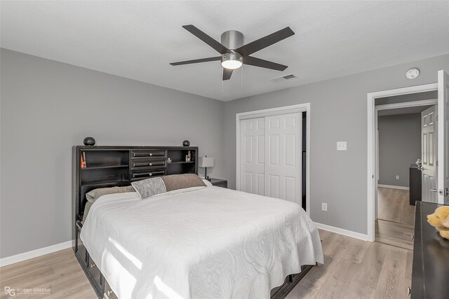 bedroom with ceiling fan, a closet, and light hardwood / wood-style flooring