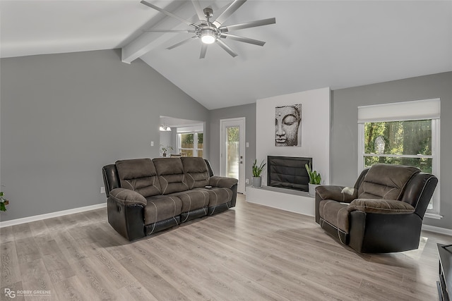 living room featuring vaulted ceiling with beams, ceiling fan, light hardwood / wood-style flooring, and a healthy amount of sunlight